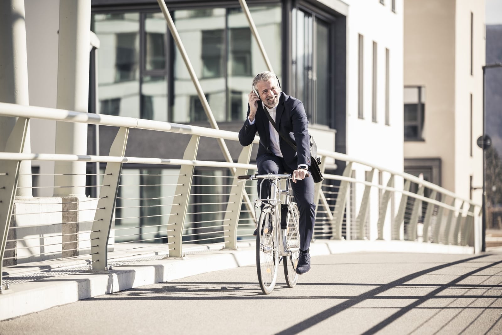 A commuter cycling across a modern city bridge on their way to work