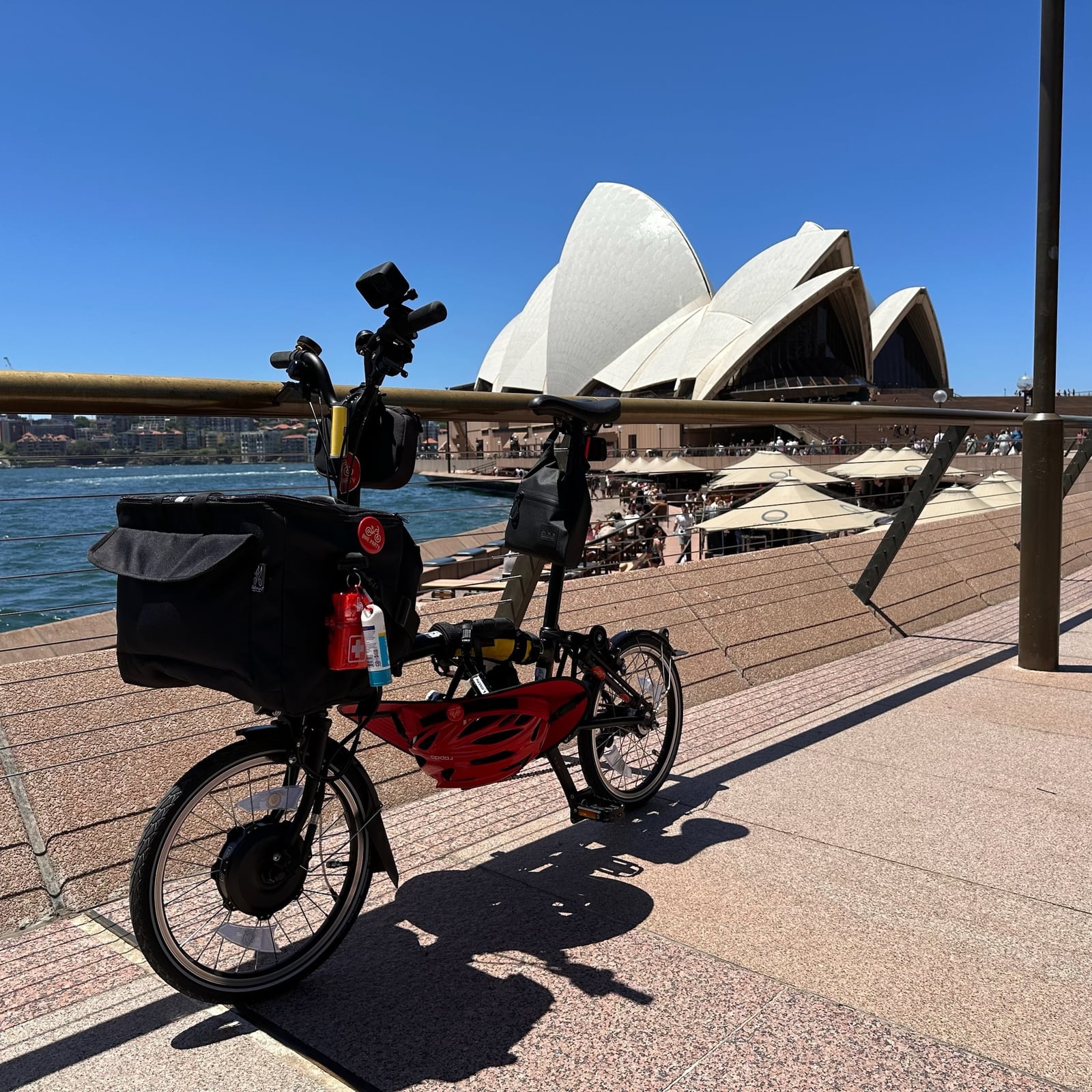 A folding bike parked in front of the Sydney Opera House on a clear day