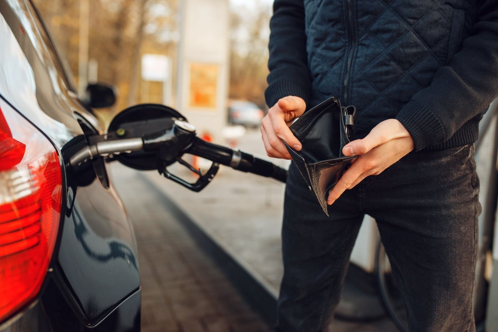 An empty wallet held open at a petrol pump